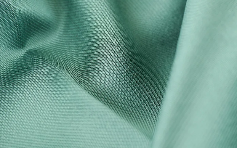 Detailed close-up shot of smooth green silk fabric texture showcasing softness and elegance.