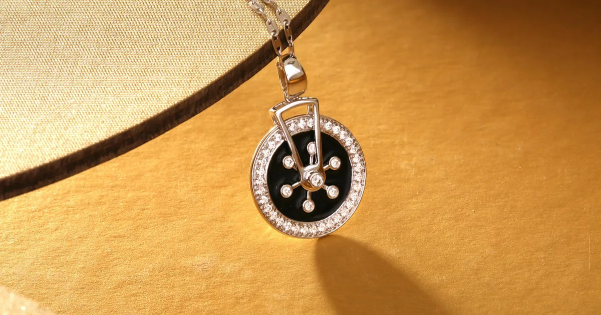 Close-up of a luxurious diamond and black pendant necklace on a gold background.