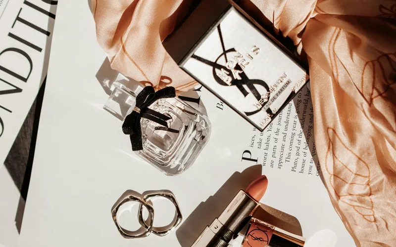 Sophisticated flat lay featuring luxury beauty products, including perfume and lipstick, with a stylish scarf.