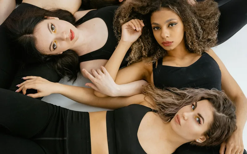 A group of diverse women posing in stylish black activewear with a confident and engaging look.