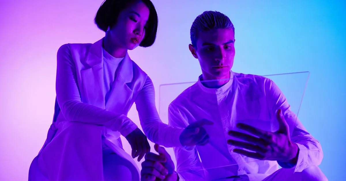 A man and woman engaging with a transparent holographic screen in a modern studio setting.