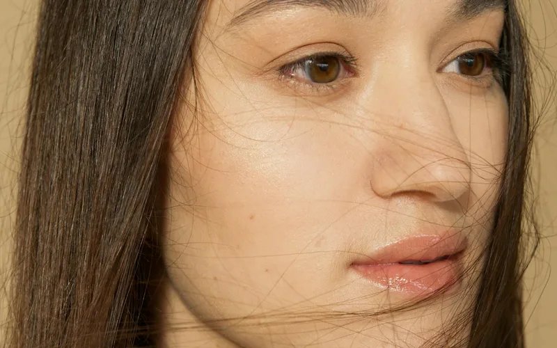 A serene close-up portrait of a woman with long, flowing hair and clear skin.