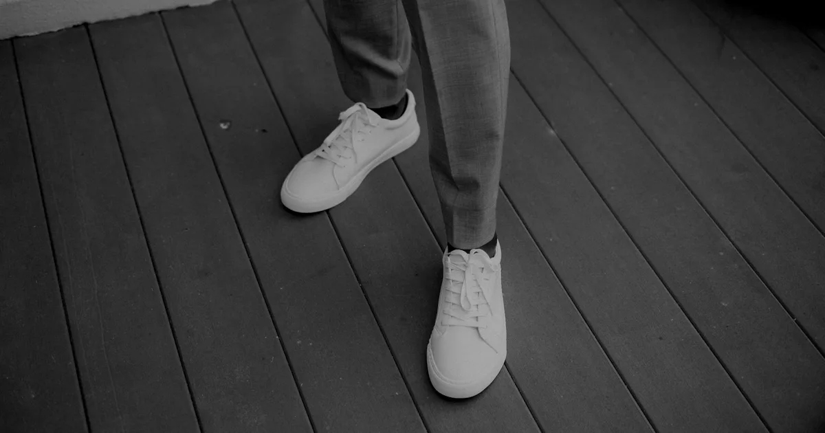 Black and white close-up of modern white sneakers on a wooden deck.