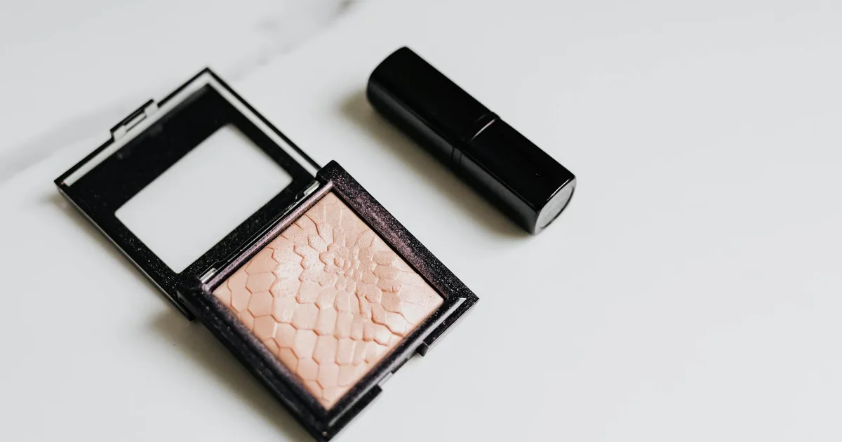 A minimalist still life featuring blush and lipstick on a clean white background for beauty and cosmetics themes.