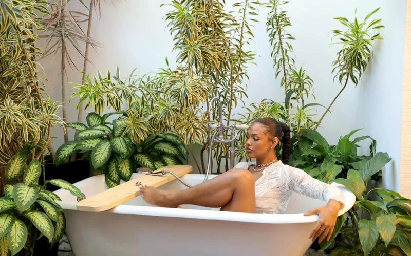 A woman enjoying a peaceful bath in an indoor tub surrounded by lush green plants.