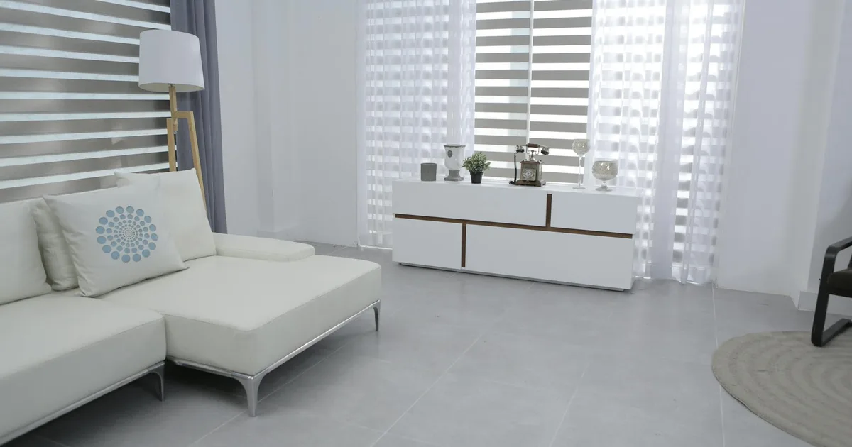 Bright and spacious living room featuring modern minimalist decor, a white sofa, and sleek furniture.