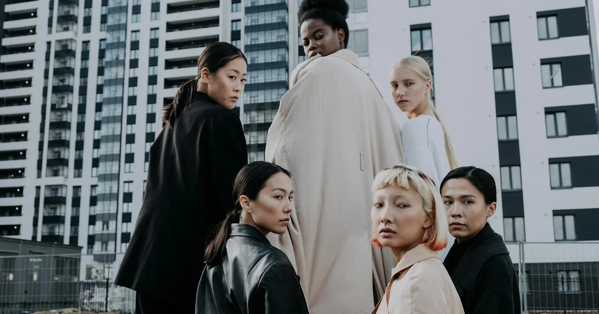 Group of diverse women modeling fashion in a modern urban setting with high-rise buildings.
