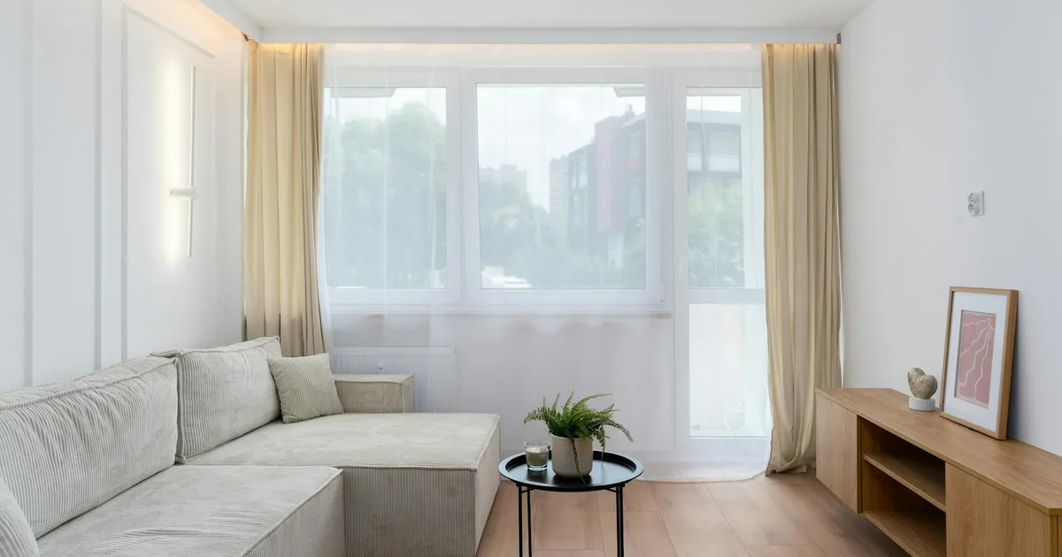 Bright minimalist living room in Kraków with modern decor, large windows, and natural light.