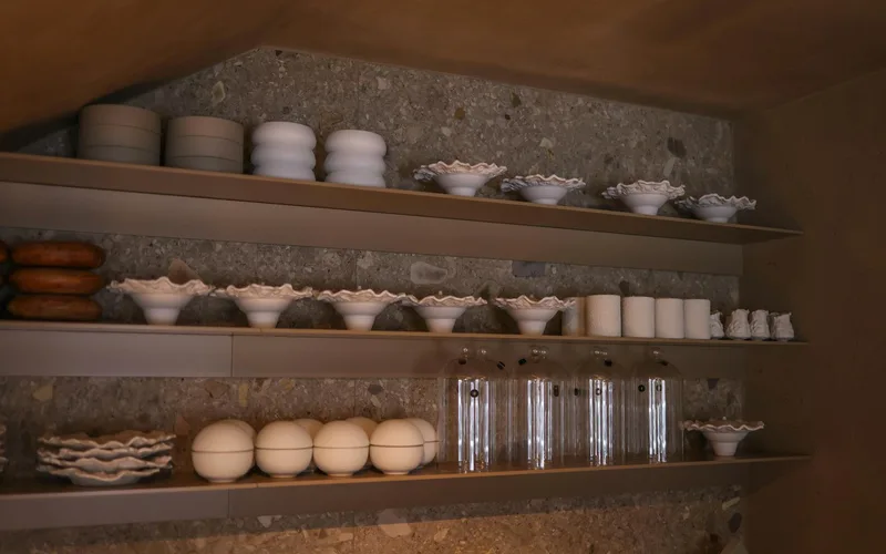 Stylish kitchen shelves display white ceramic dishes and glassware in a modern interior.