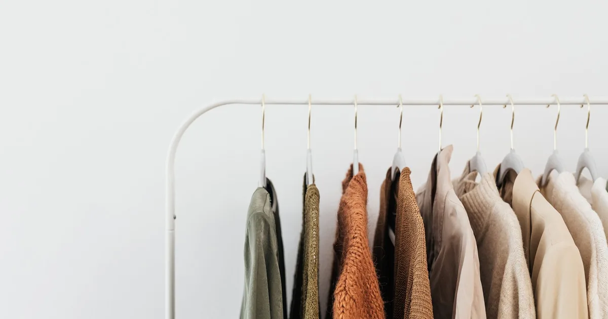 A minimalist clothing rack displaying neutral-toned outfits in an organized indoor setting.