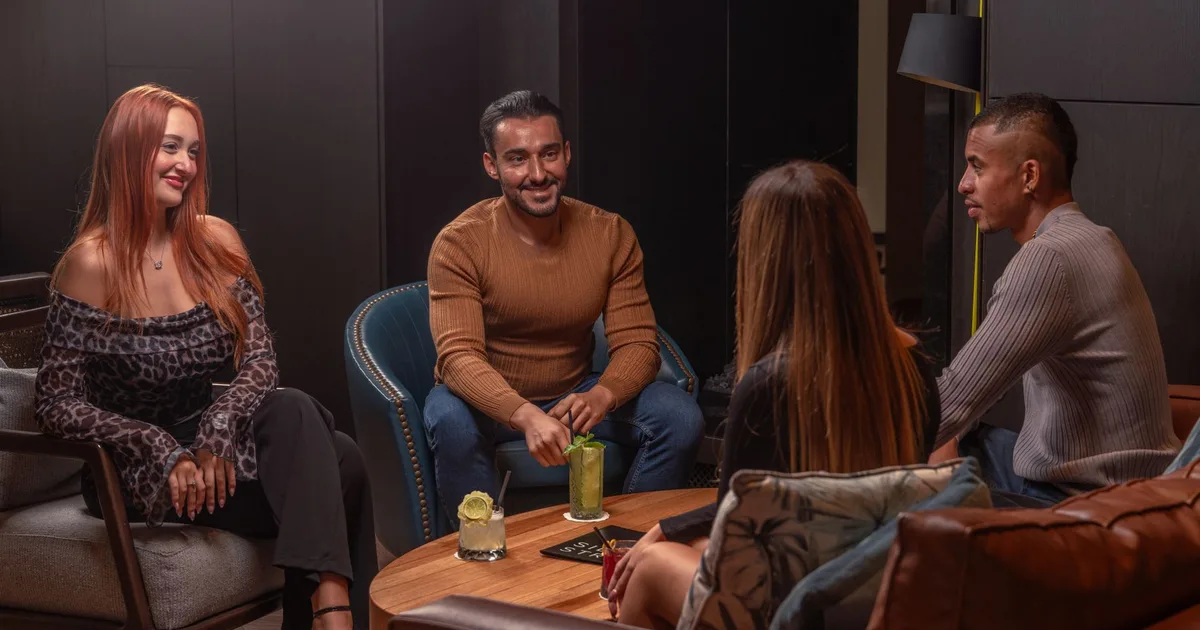 A diverse group enjoying drinks and conversation in a modern lounge setting.