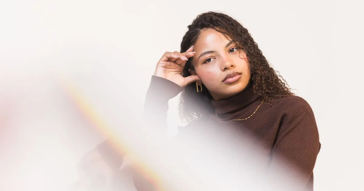 Elegant portrait of a woman in a brown sweater, soft focus and muted background enhance the sophisticated look.