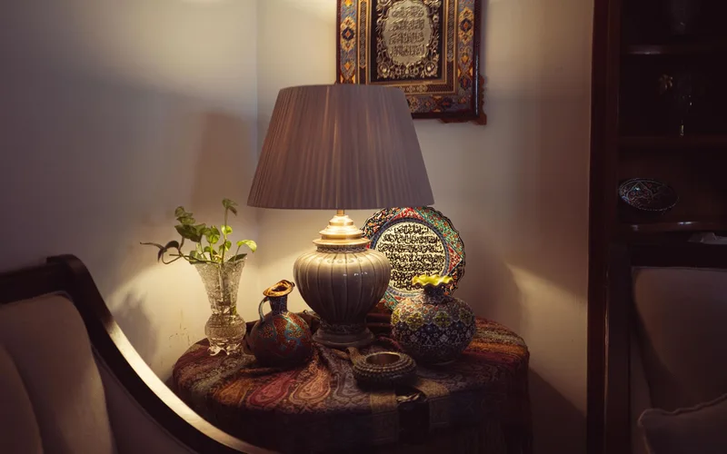A warm, cozy living room corner with a decorative lamp, ceramics, and art, creating a bohemian atmosphere.