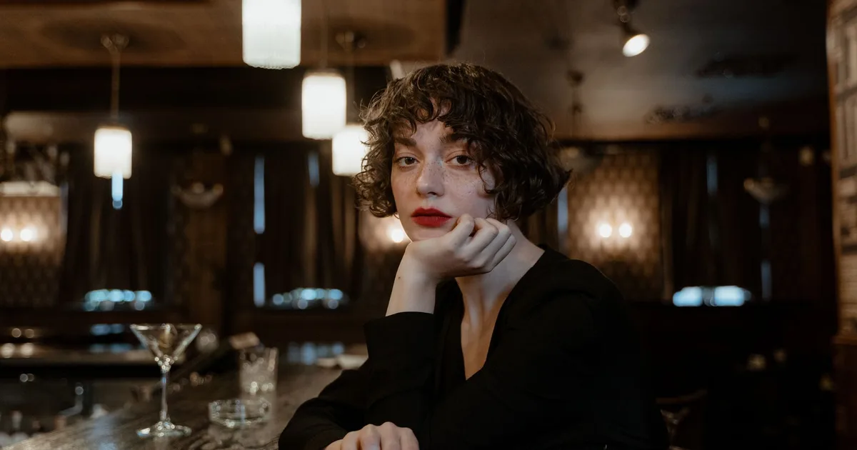 A fashionable woman with short hair in a classic bar setting, exuding elegance and style.