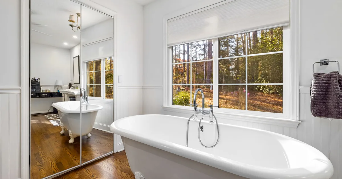 Bright bathroom with a classic clawfoot bathtub, large glass windows, and elegant decor. Perfect for interiors.