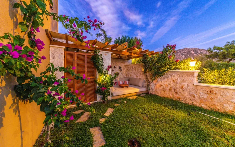 A cozy garden patio with vibrant flowers under a wooden pergola at twilight.
