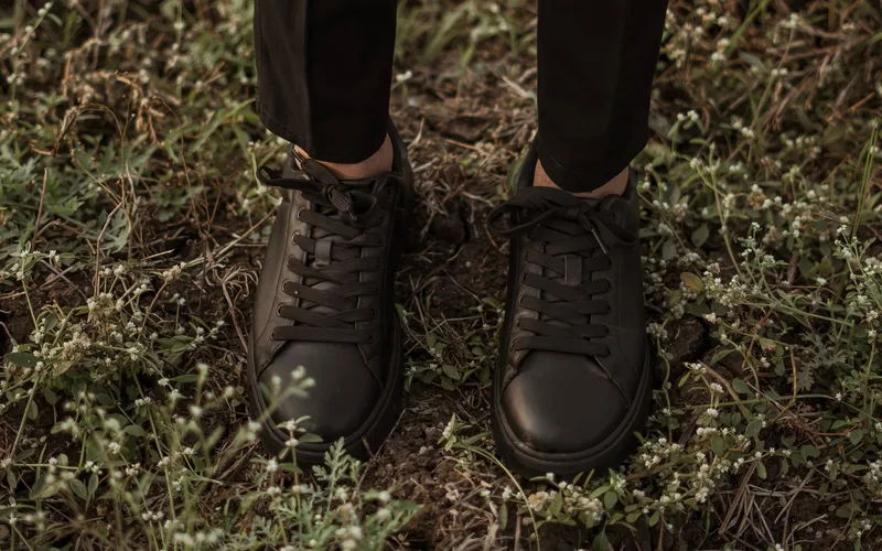 Close-up of stylish black leather shoes standing on grass, capturing a modern fashion vibe.