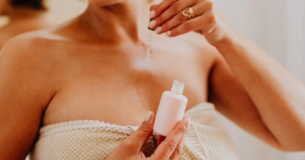 Close-up of a woman applying serum to her skin, enhancing beauty routine.