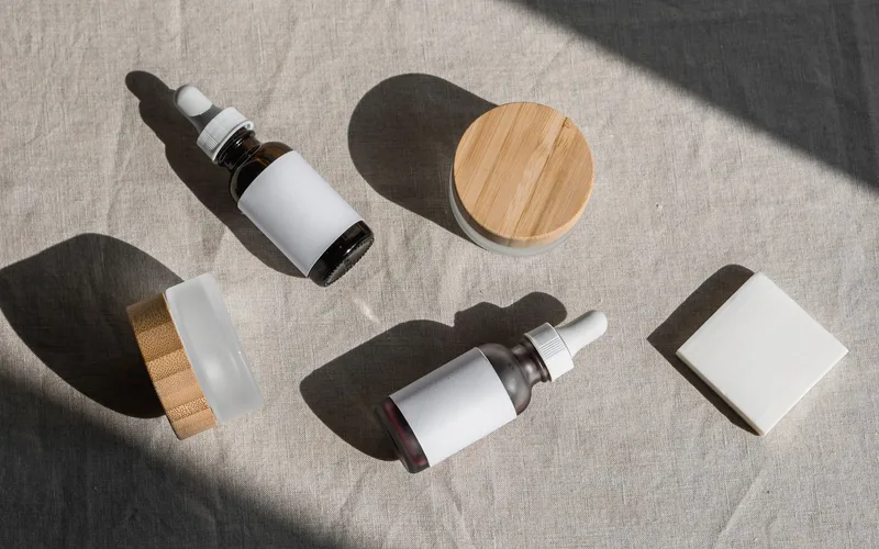 A minimalist flat lay of cosmetic bottles and jars on a linen cloth, perfect for beauty product presentations.