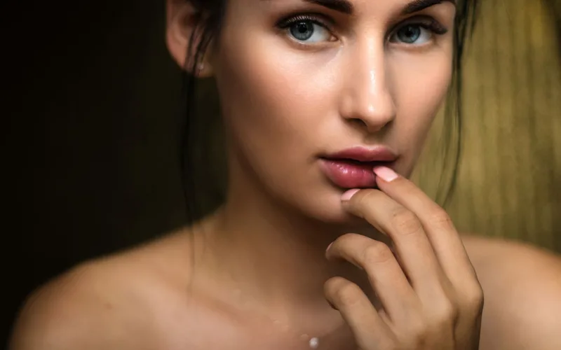Close-up portrait capturing a woman's natural beauty with soft lighting and a thoughtful expression.