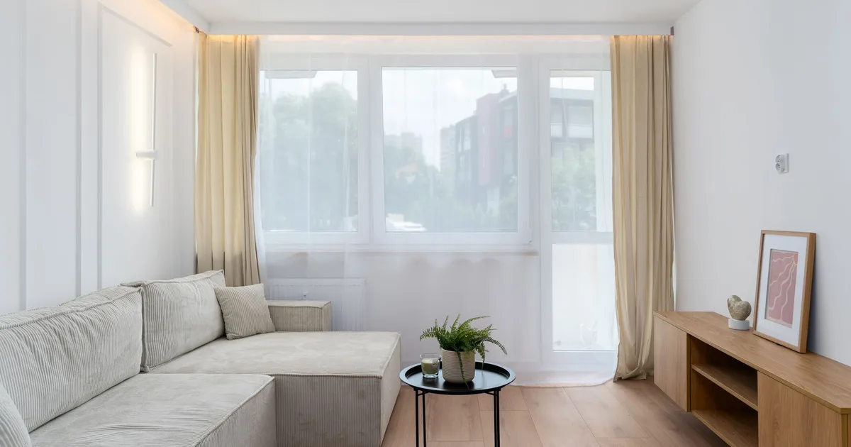 Bright minimalist living room in Kraków with modern decor, large windows, and natural light.