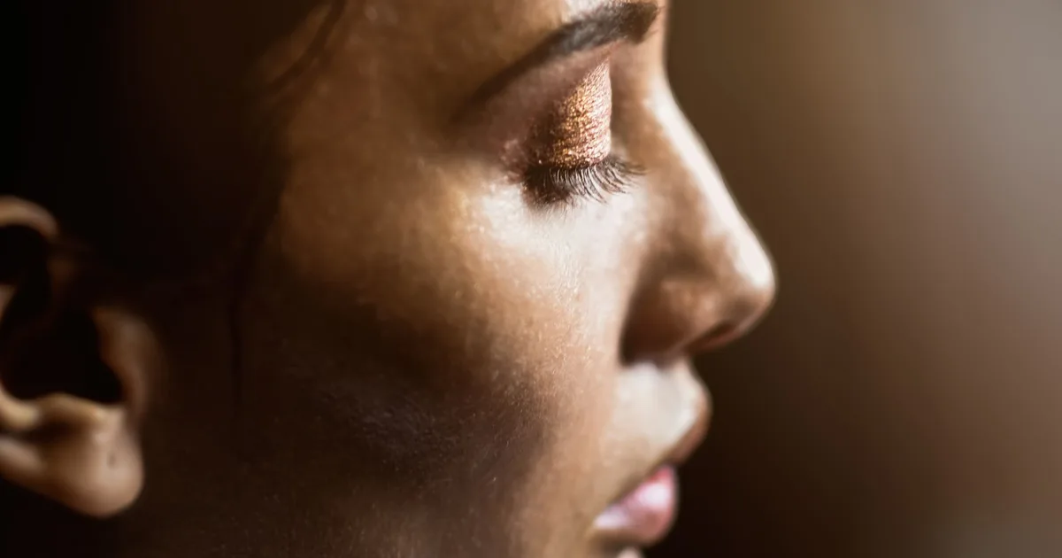 Artistic side profile of a woman's face highlighting skin texture and eye makeup.