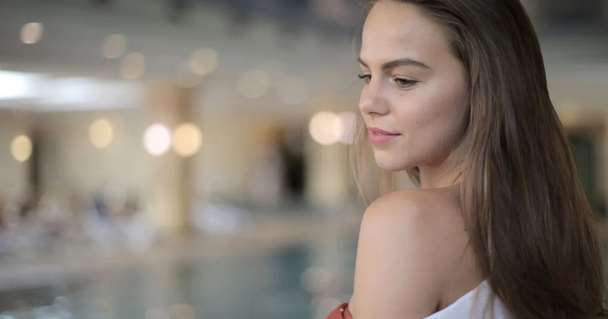 Portrait of a woman relaxing indoors by the pool with soft lighting.