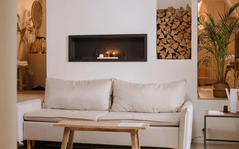 A serene minimalist living room featuring a clean lined sofa, wooden accents, and ambient candles.