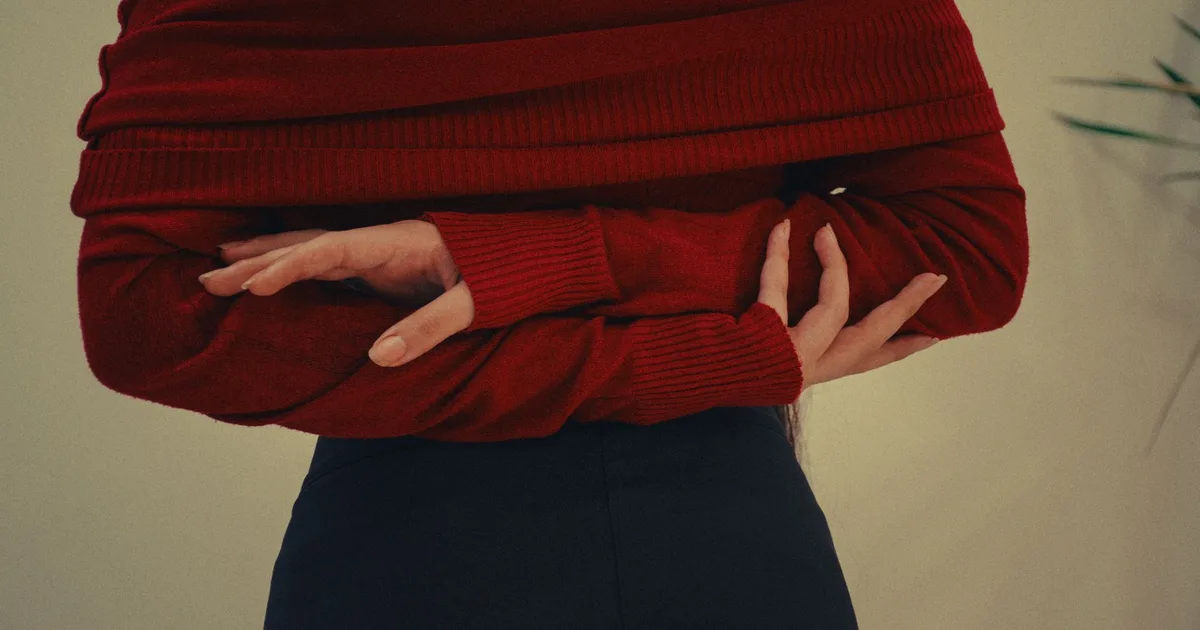 Artistic portrait of a woman in a red sweater, captured in a minimalistic studio setting.