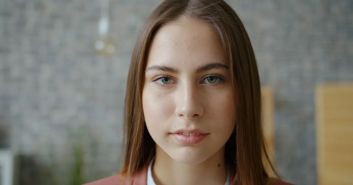 Close-up portrait of a young woman with a serene expression indoors.