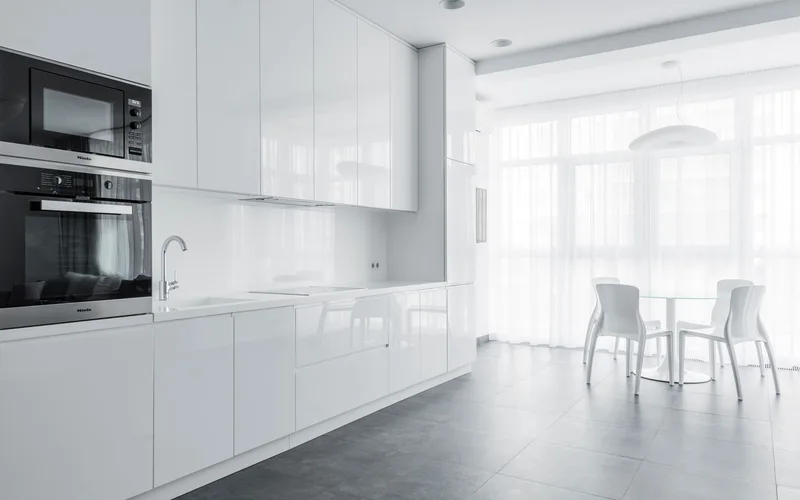 Bright minimalist kitchen with sleek white cabinets and dining area, perfect for modern home designs.
