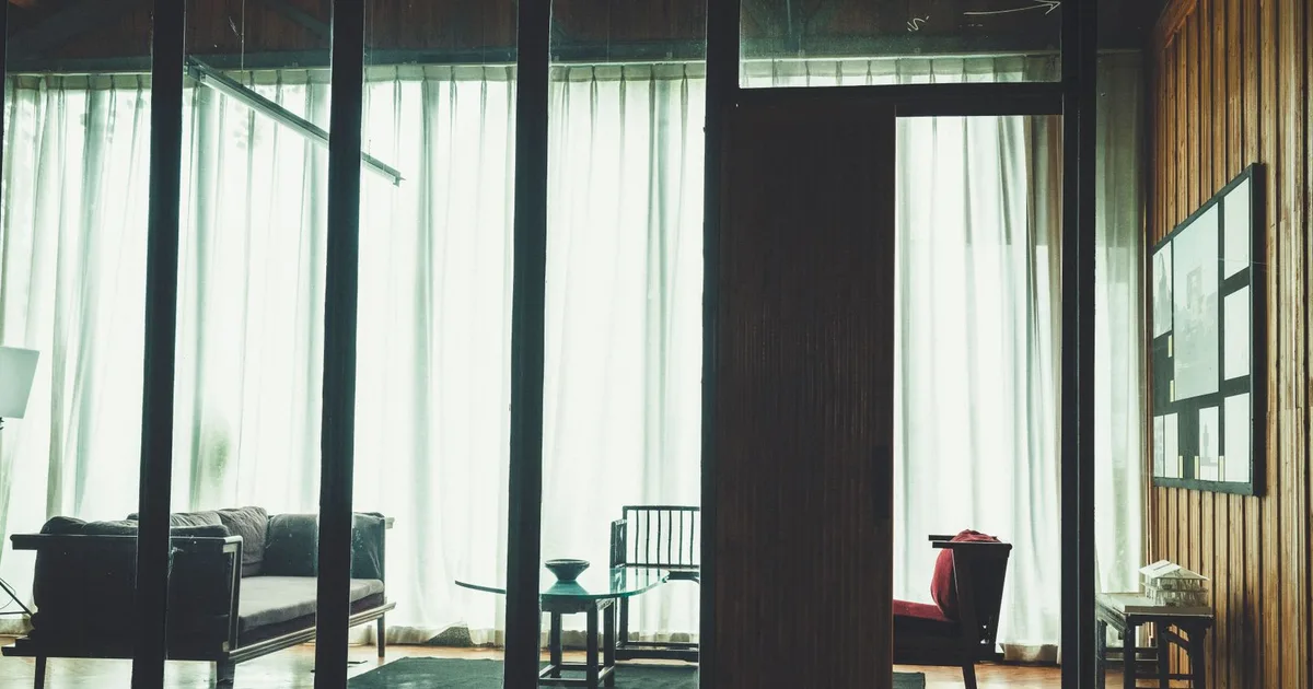 A stylish, minimalist living room with large windows and natural light streaming in.