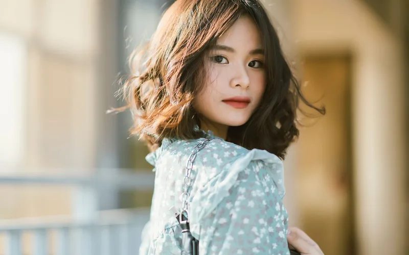 Elegant portrait of an Asian woman wearing a floral dress outdoors.